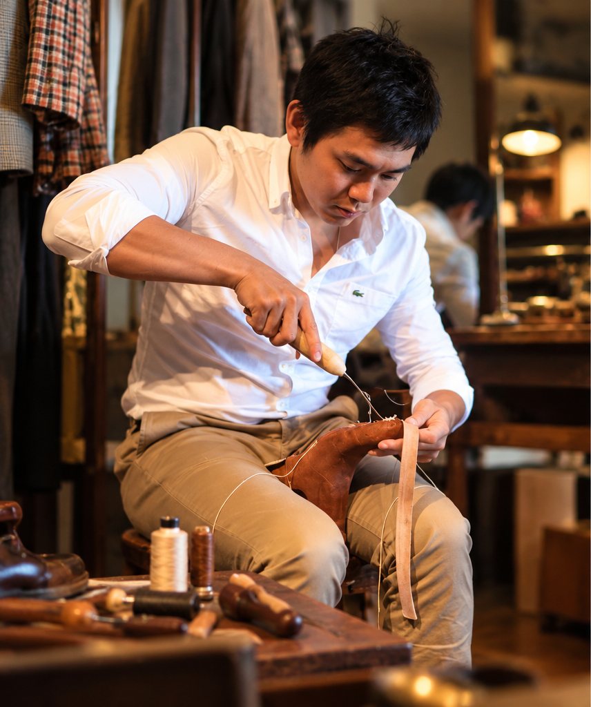 Bell hand-stitching a shoe at his workbench