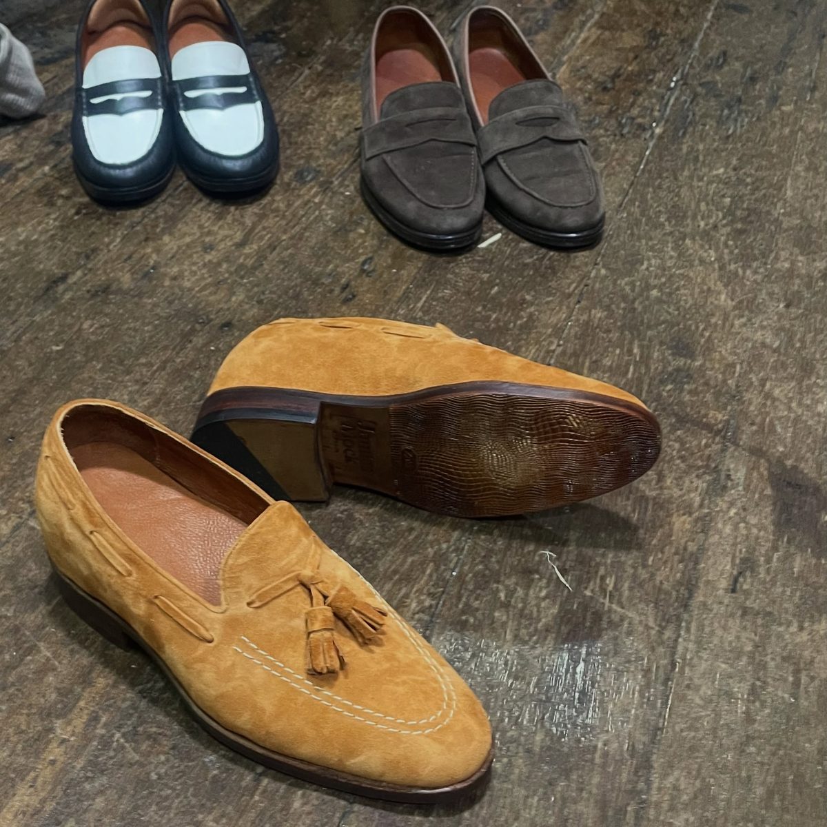 Tan suede tassel loafer with penny loafers behind