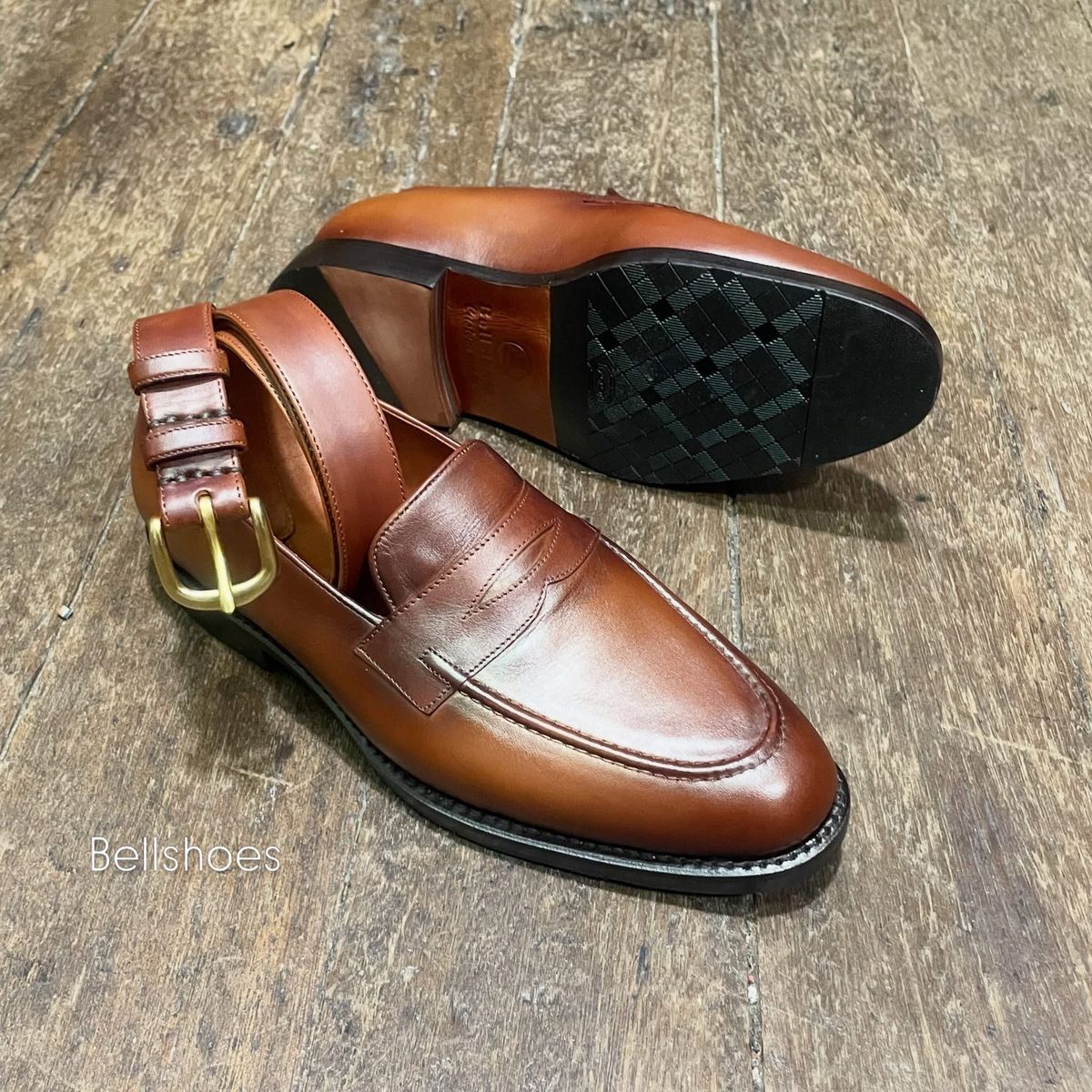 Tan penny loafer with a brass-buckle belt
